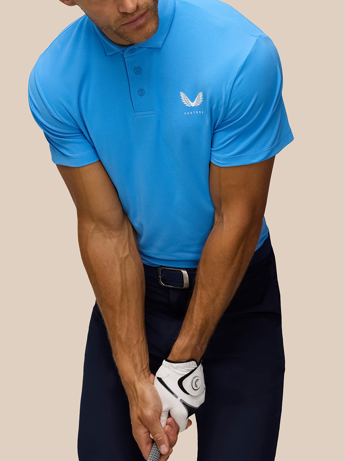Front view of a golfer wearing a Cool Blue Golf Club Essential Polo with Castore logo on the left chest and polo collar