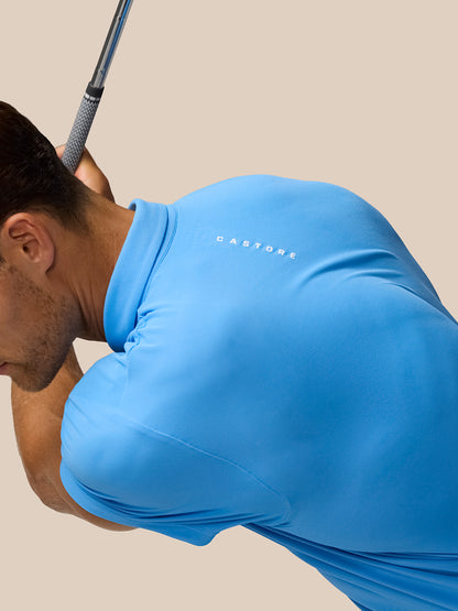 Side view of a golfer in a Cool Blue Golf Club Essential Polo with Castore logo visible on the chest as they prepare to swing
