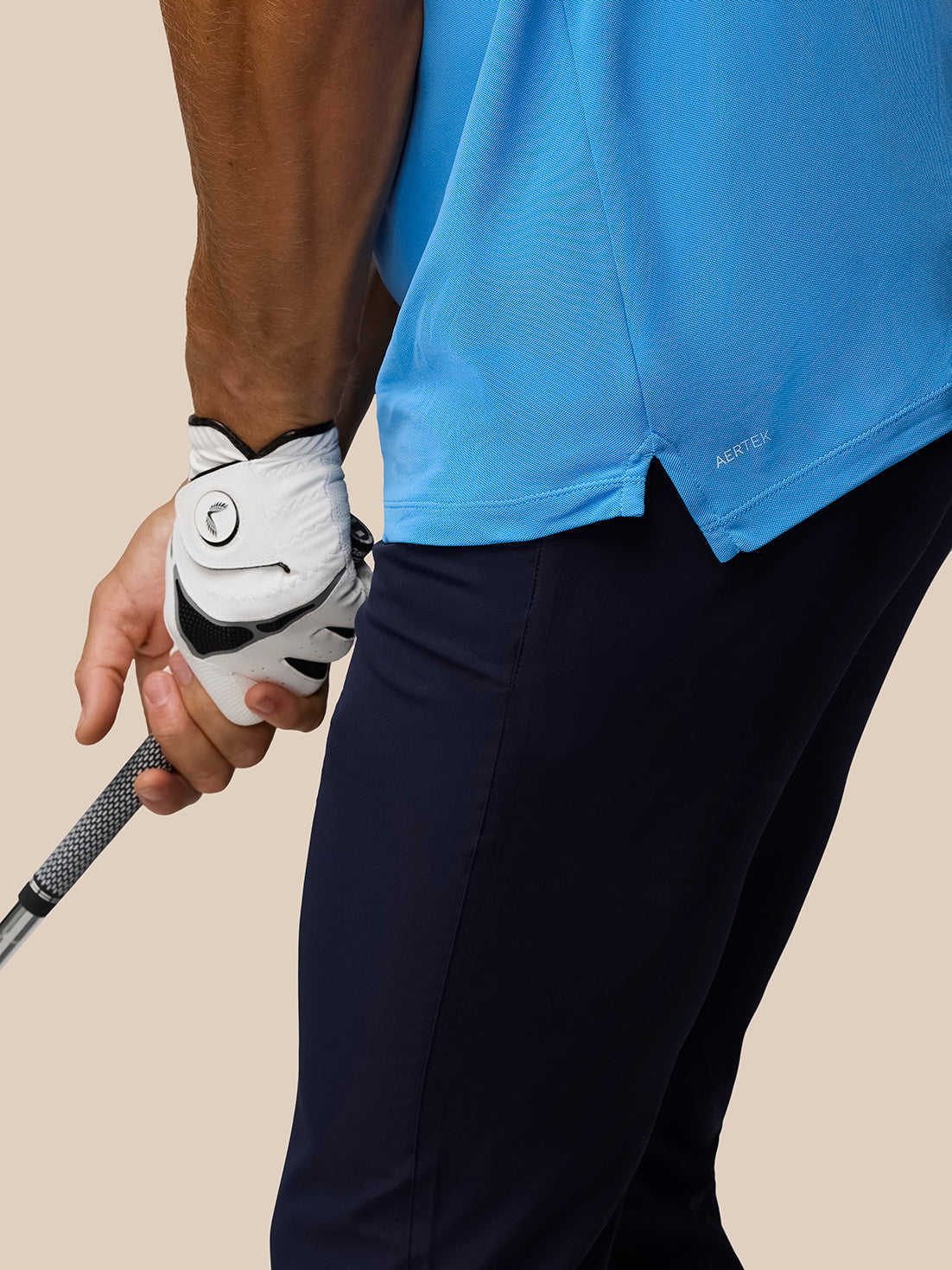 Golfer in a Cool Blue Golf Club Essential Polo gripping a club showcasing AerTek moisture-wicking fabric and split hem