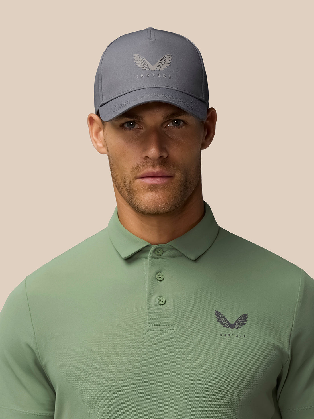 Male model wearing Thyme Golf Club Essential Polo in sage green with a gray cap