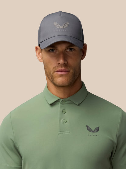 Male model wearing Thyme Golf Club Essential Polo in sage green with a gray cap