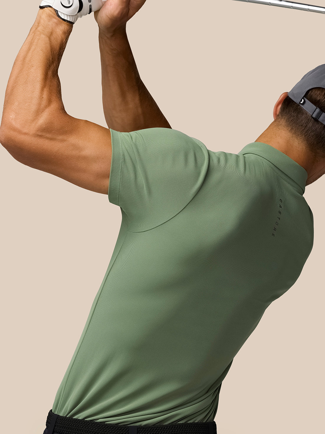 Back view of a golfer in the Thyme Golf Club Essential Polo during a swing with Castore branding on the shirt