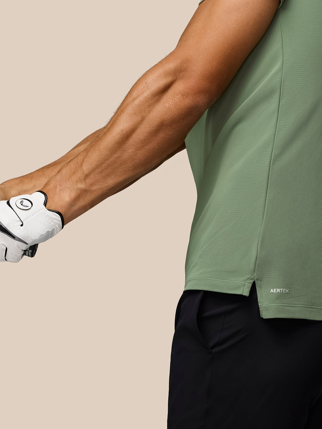 Close up of a golfer wearing the Thyme Golf Club Essential Polo with AerTek branding at the hem