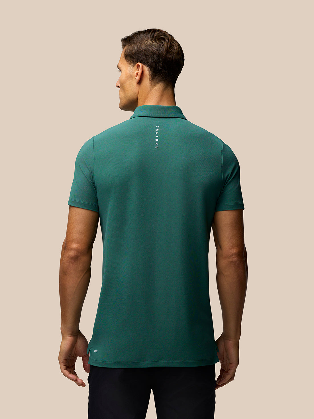 Back view of a man wearing a green Club Golf Polo showing Castore branding down the center back.
