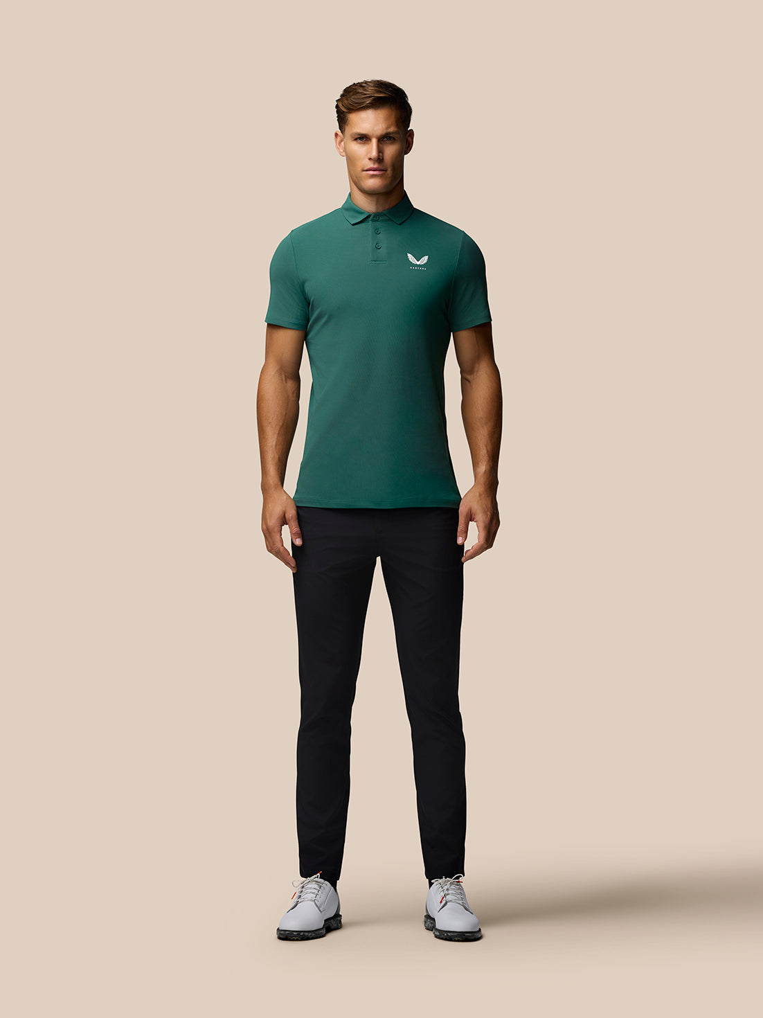Front view of a man in a green Club Golf Polo with left chest Castore logo.