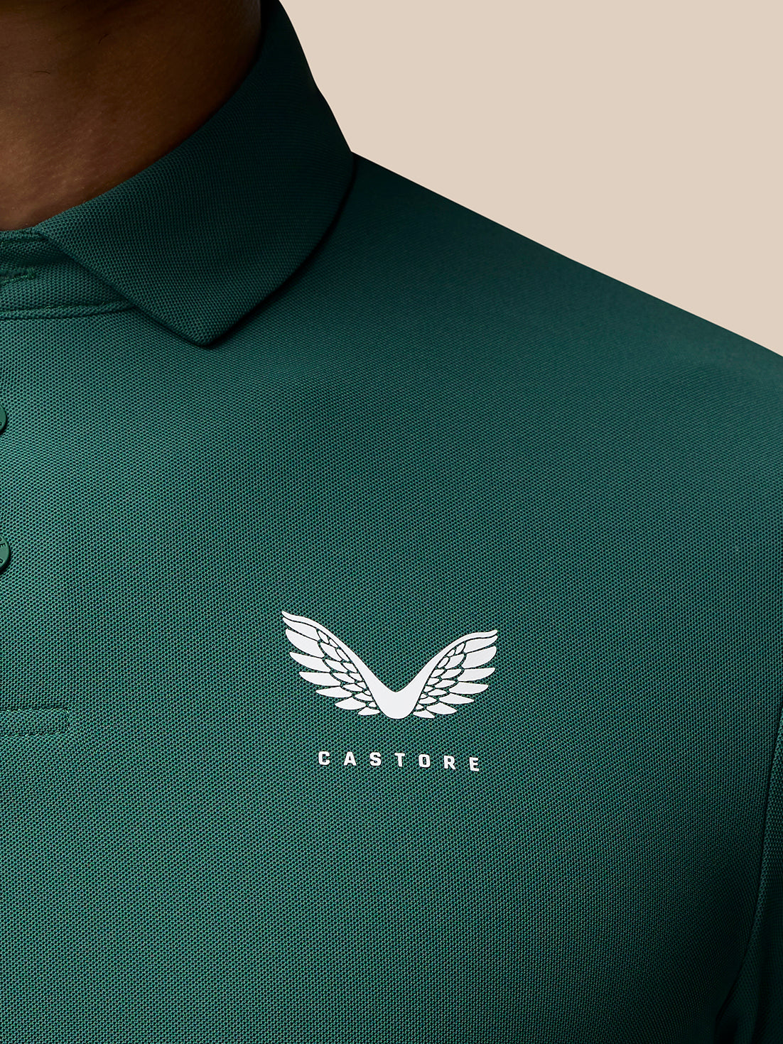 Close-up of green Club Golf Polo fabric with left chest white Castore logo.