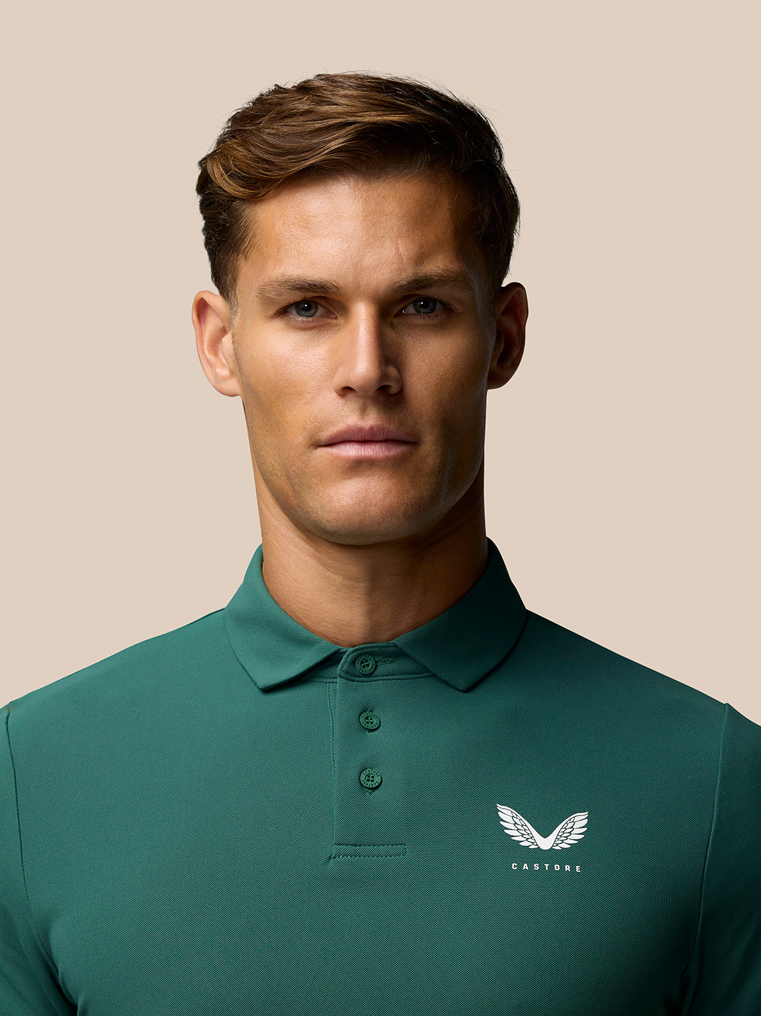 Male model wearing green Castore Club Golf Polo with three button placket and chest logo