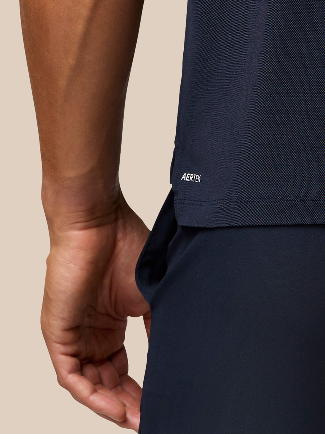 Back view of a man in navy golf polo with Aertek branding at the lower back and Castore branding on the upper back