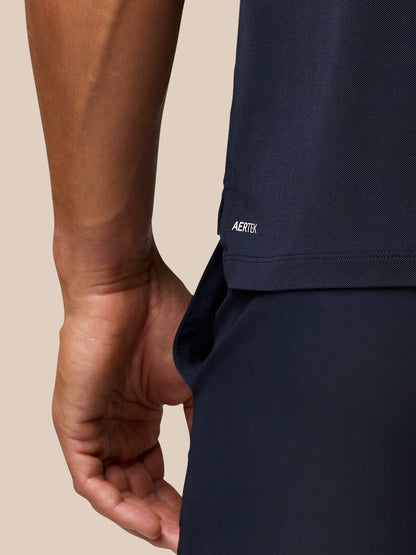 Back view of a man in navy golf polo with Aertek branding at the lower back and Castore branding on the upper back