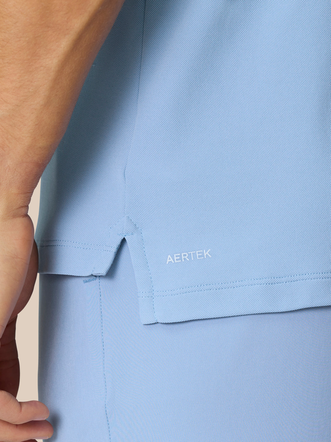 Close-up of sky blue Golf Club Essential Polo fabric with Aertek branding near the hem