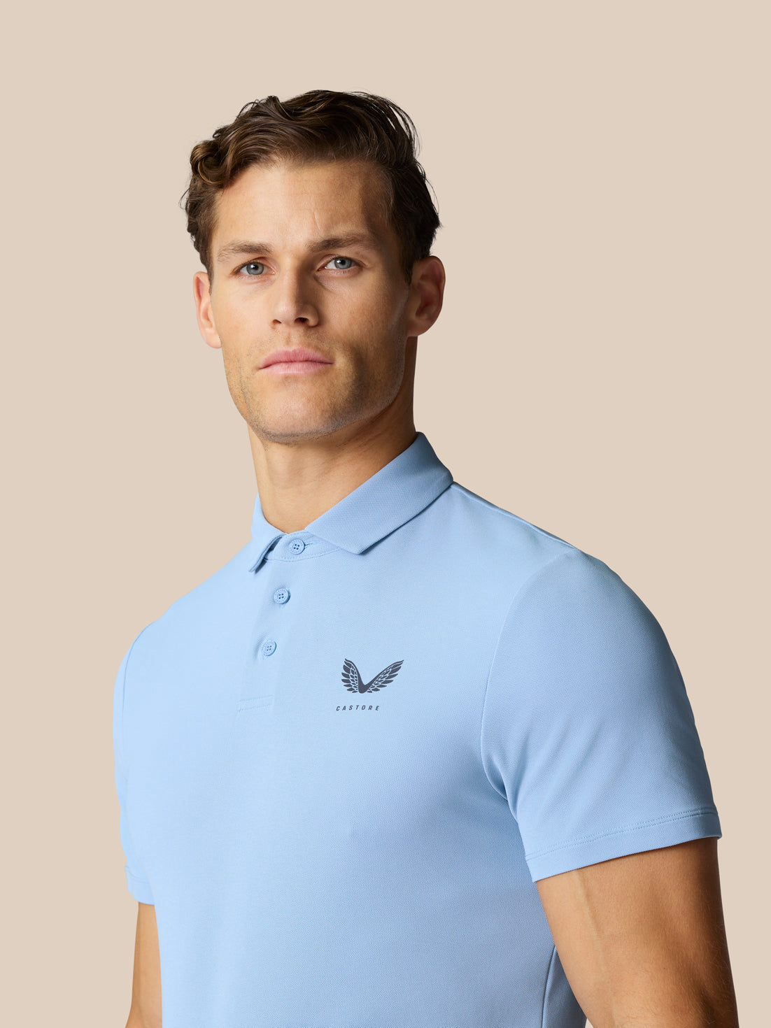Male model wearing sky blue Golf Club Essential Polo with logo on chest and matching shorts