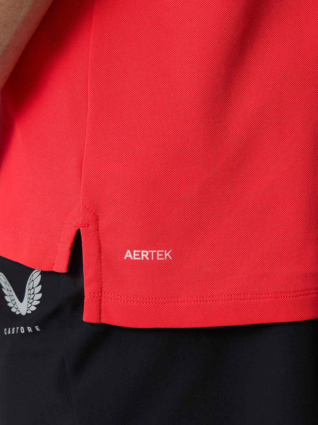 Close up of red golf polo fabric with Aertek branding near the hem