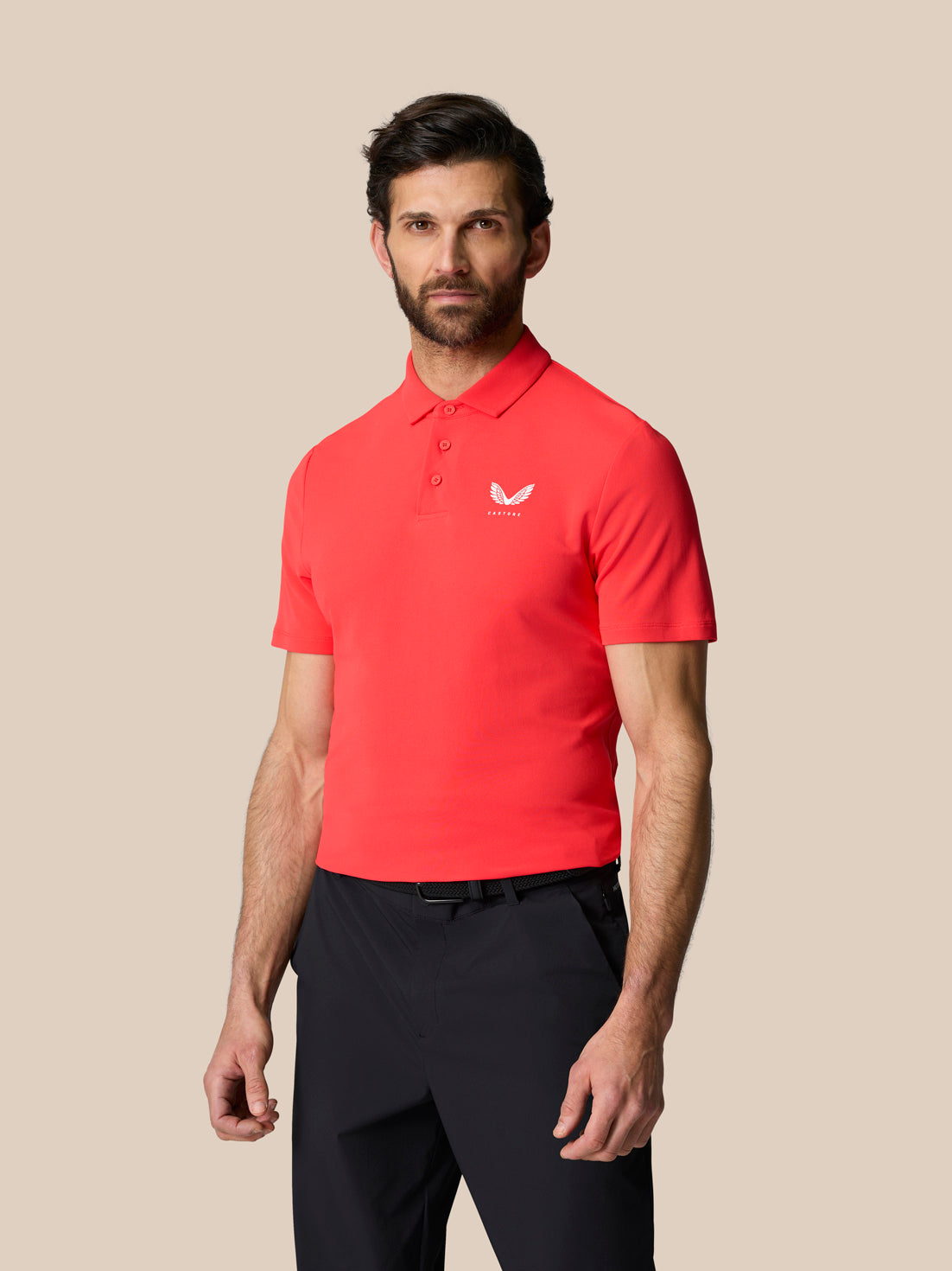 Male model wearing bright red short sleeve polo with button collar and Castore logo on left chest