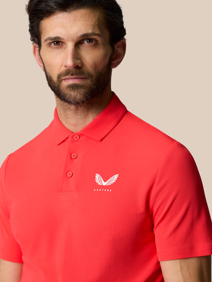 Close-up of a man in a red Golf Club Essential Polo showing Castore logo on the left chest.