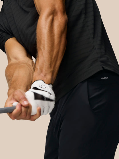Close up of a golfer in a black Pinnacle Polo gripping a club during a swing showing striped knit fabric and glove