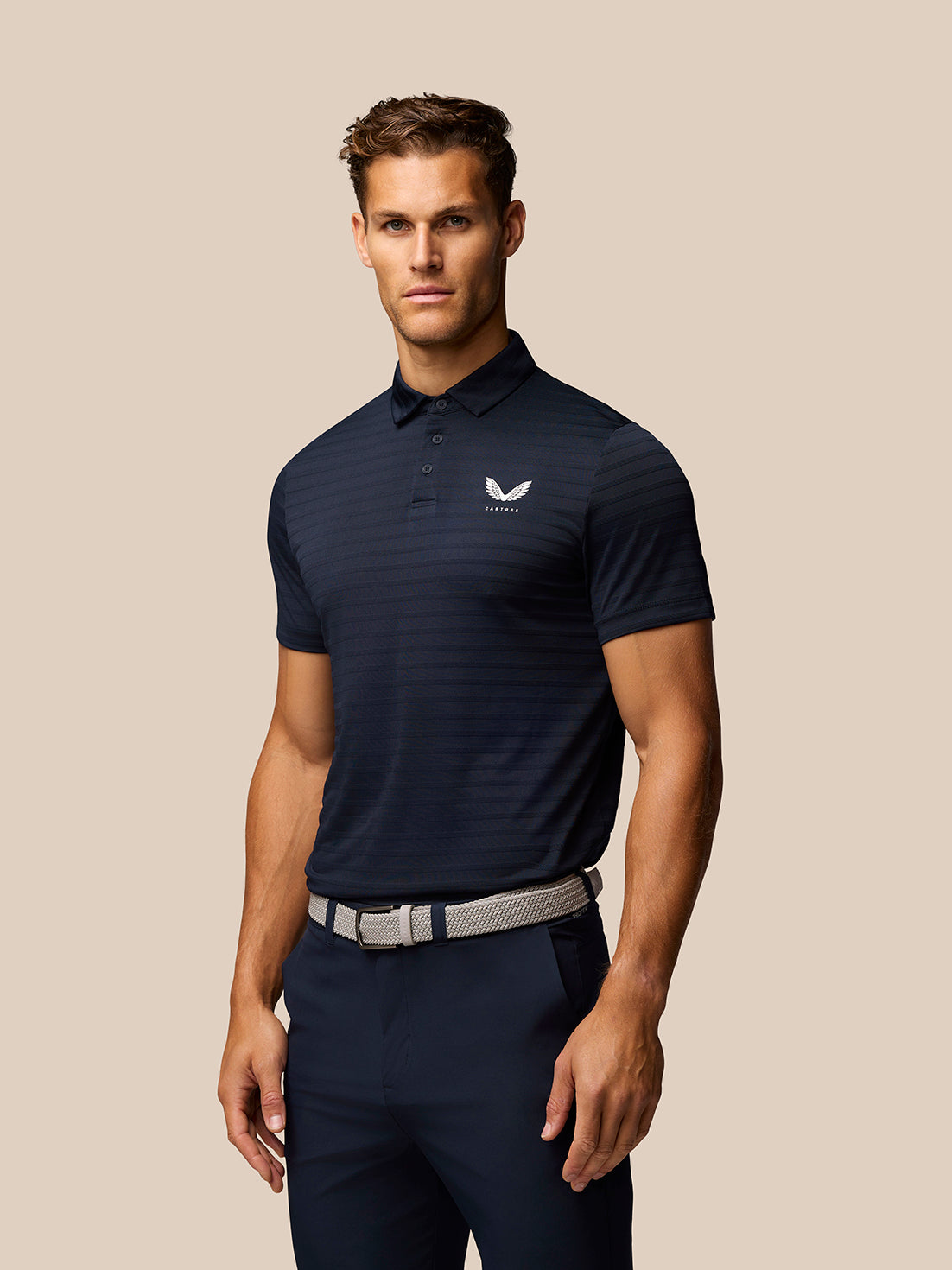 Male model in navy Pinnacle Pique Stripe Polo with subtle horizontal stripes and Castore logo on chest
