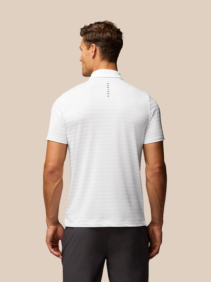Back view of a male model wearing a white textured pique stripe polo with subtle stripe pattern