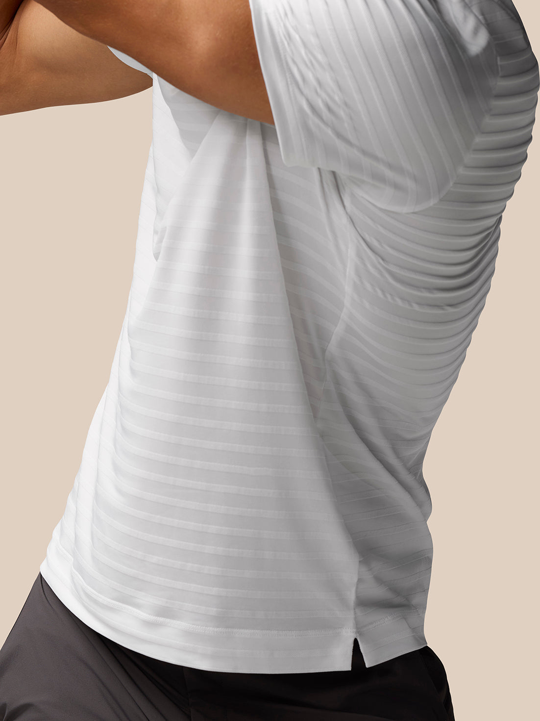 Profile view of white striped polo showing Castore branding running vertically along the back.