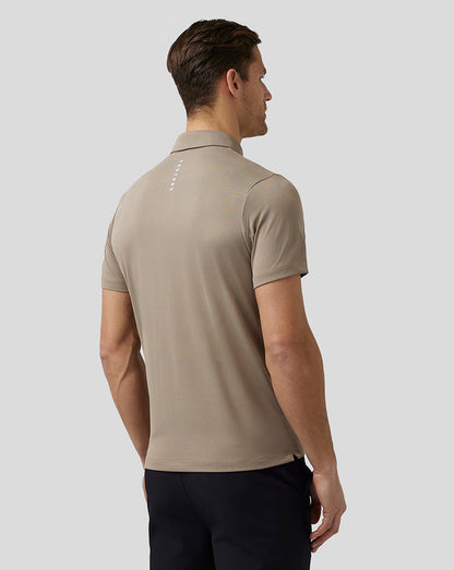 Back view of beige Pinnacle Knit Polo on a man showing Castore branding on the upper back and Aertek branding at the lower back