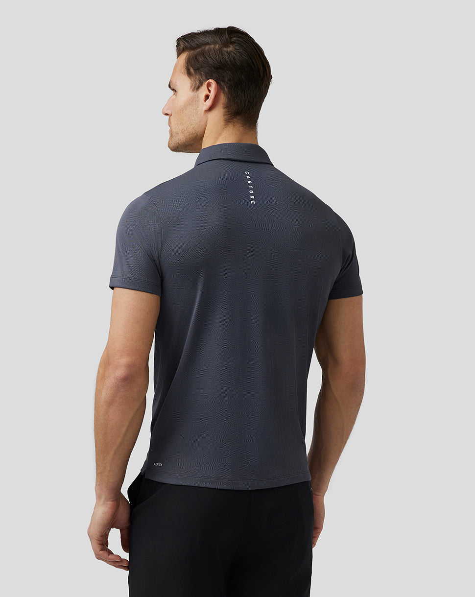 Back view of a man wearing a dark pewter Pinnacle Knit Polo with Castore branding along the upper back