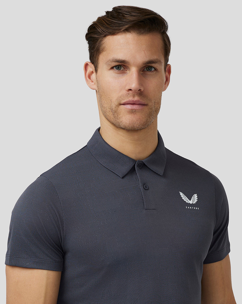 Male model wearing pewter Pinnacle Knit Polo with textured pattern and Castore logo on chest