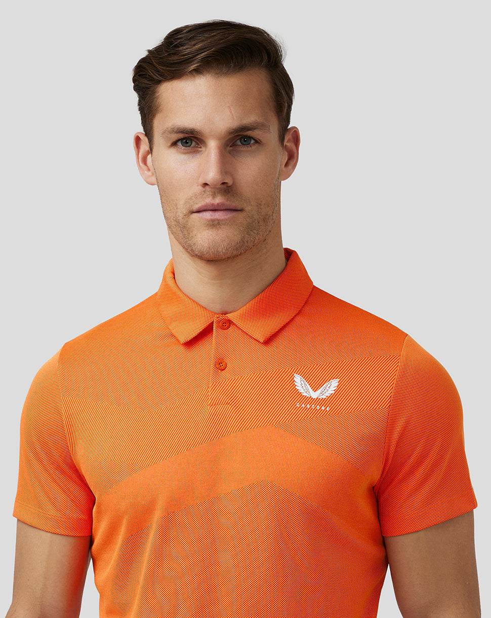 Male model wearing deep orange textured golf polo with three button placket and Castore logo on left chest