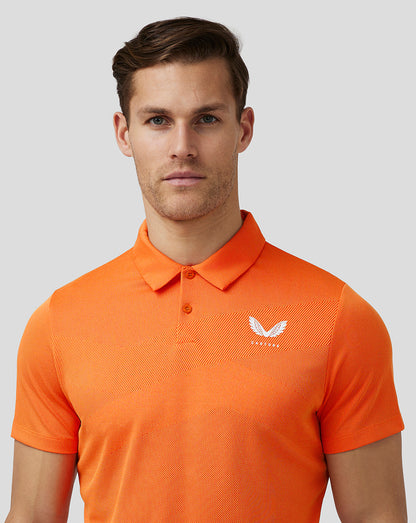 Male model wearing deep orange textured golf polo with three button placket and Castore logo on left chest