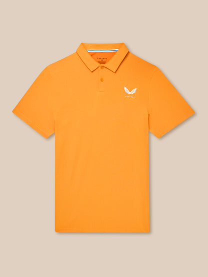 Flat lay of orange Golf Pinnacle Polo Mango with collar and chest logo against a beige background.