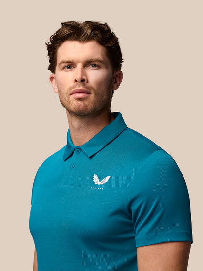 Male model wearing teal Pinnacle golf polo with Castore logos on chest and upper back