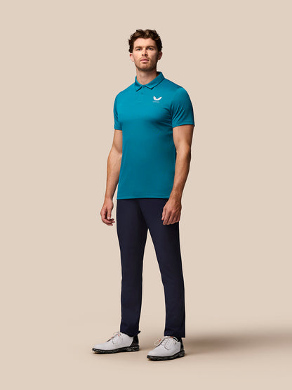 Front angled shot of a man in teal Pinnacle golf polo displaying Castore logo on chest