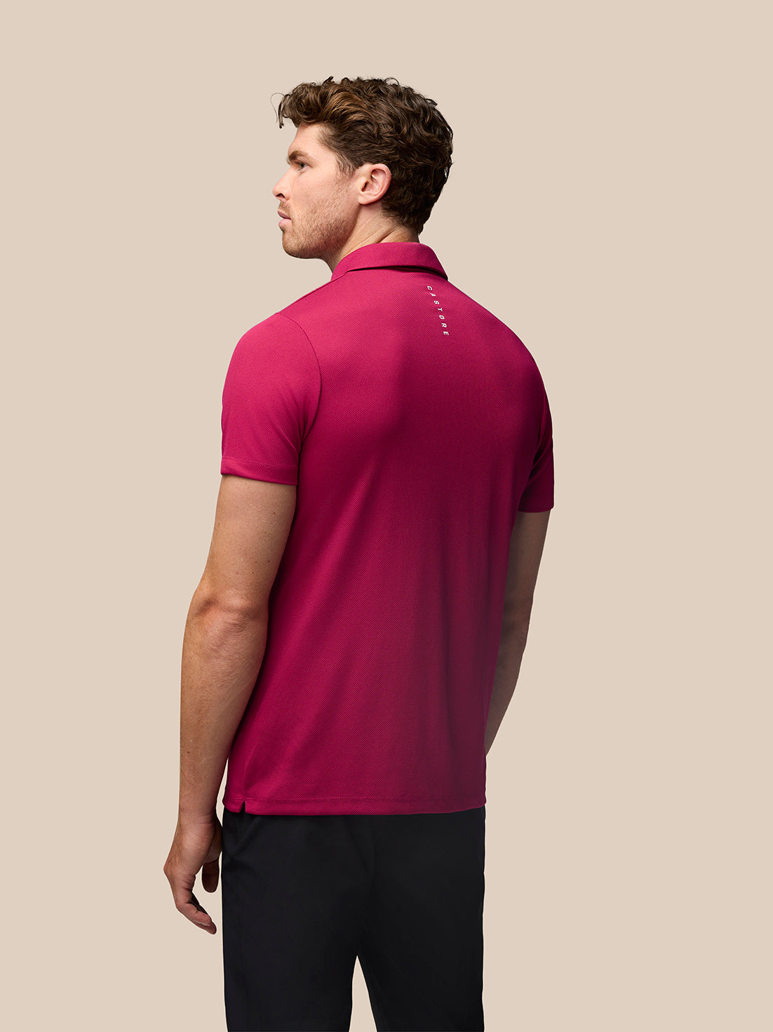 Back view of man in pink Pinnacle polo showing Castore branding along the upper back.