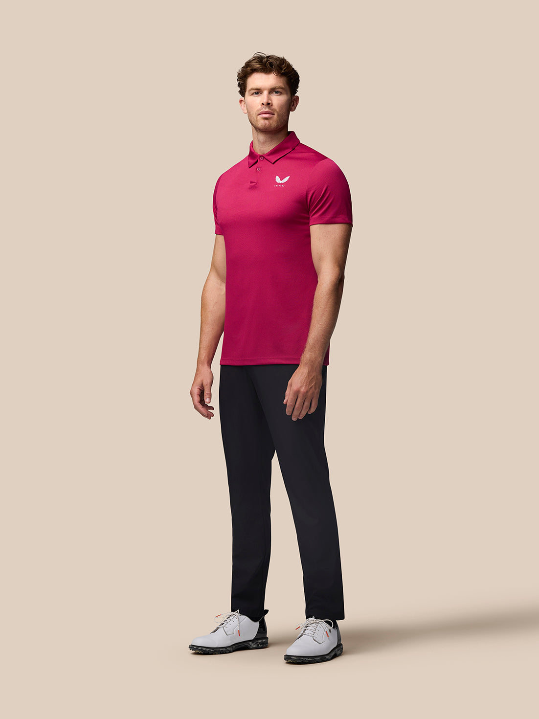 Male model wearing pink Pinnacle Golf Polo with white Castore logo on chest and upper back