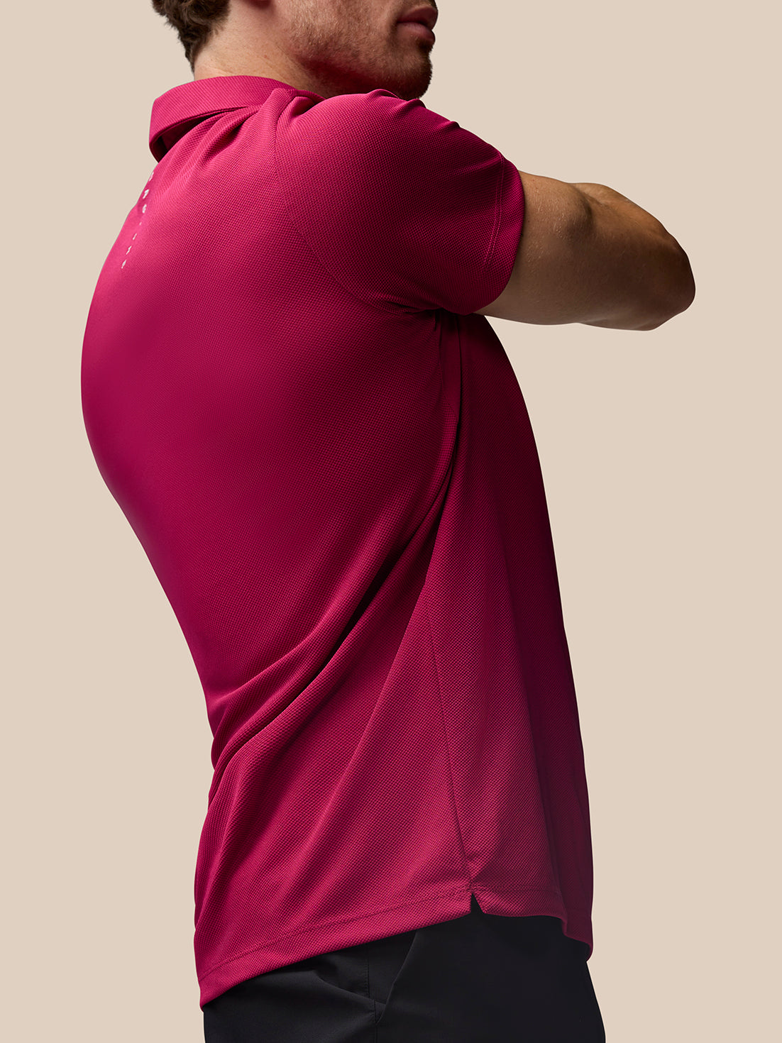 Back view of a man in a pink Pinnacle Golf Polo showing Castore branding running vertically along the back.