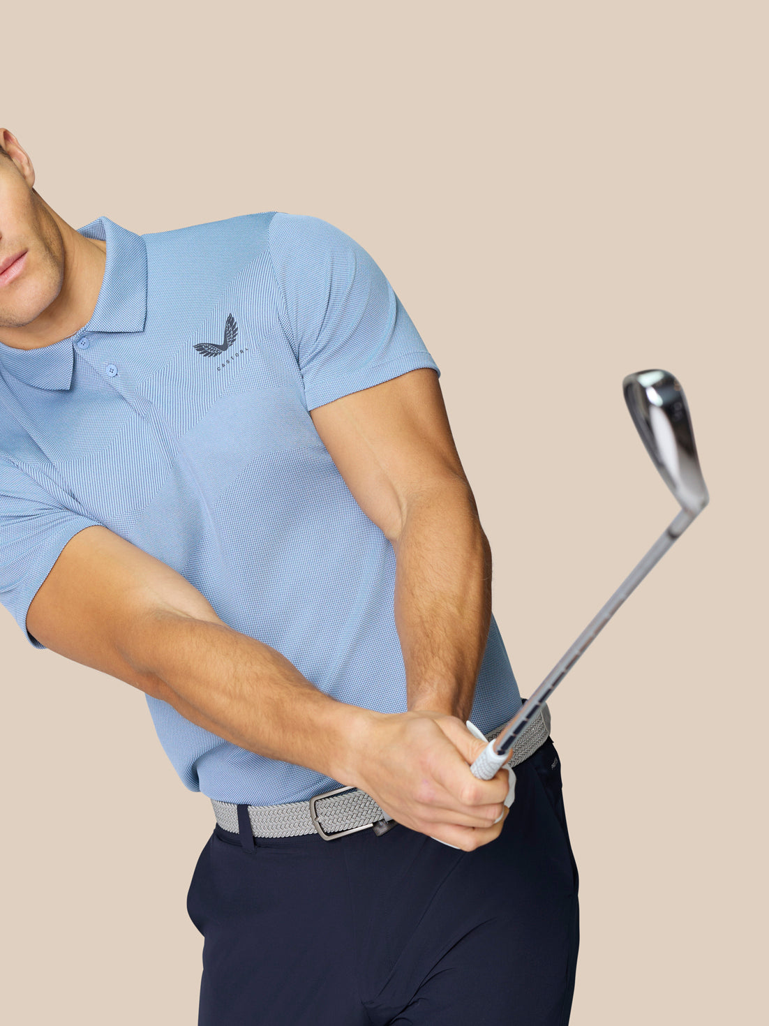 Man wearing sky blue engineered knit polo from a rear three quarter view, featuring textured knit and back branding.