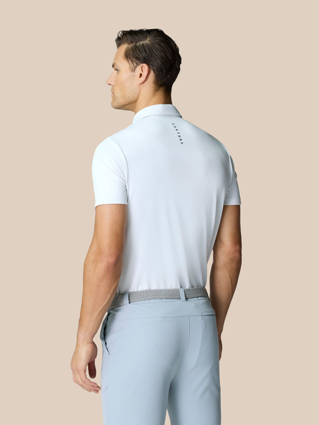 Back view of man in white Golf Pinnacle Polo with Castore branding along the upper back