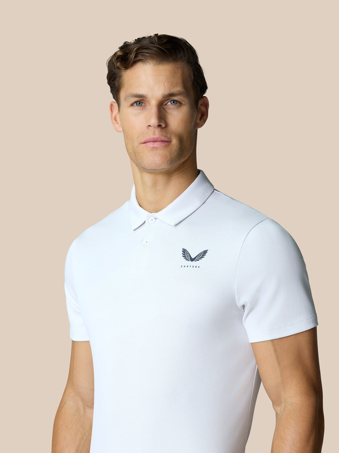 Front view of a male model wearing the white Golf Pinnacle Polo, featuring breathable knit and chest logo
