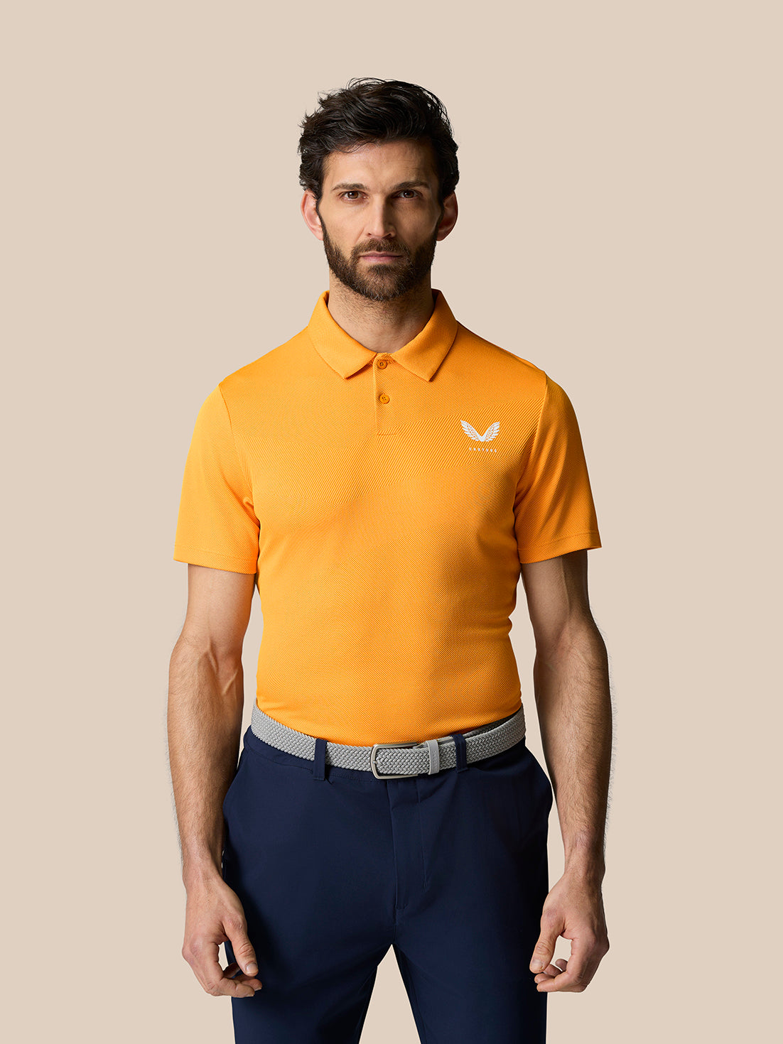 Male model wearing bright orange Golf Pinnacle Polo with pointed collar and short sleeves