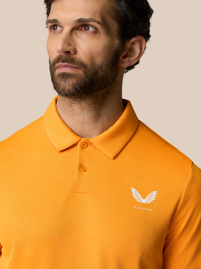 Male model wearing bright orange Golf Pinnacle Polo Mango with a pointed collar and Castore logo on the chest.