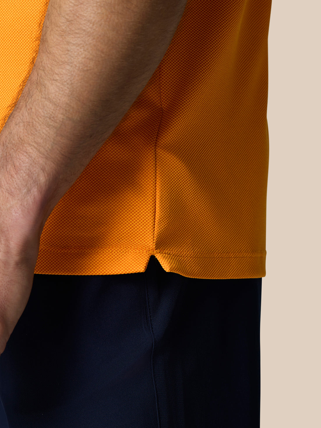 Close-up of textured knit fabric and side hem slit on the Golf Pinnacle Polo Mango.