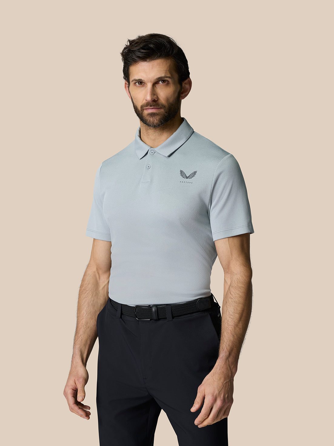 Male model wearing mid grey golf polo with short sleeves and breathable textured knit.