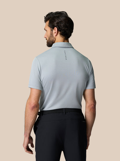 Back view of a man in a mid grey engineered knit polo with branding on the upper back.
