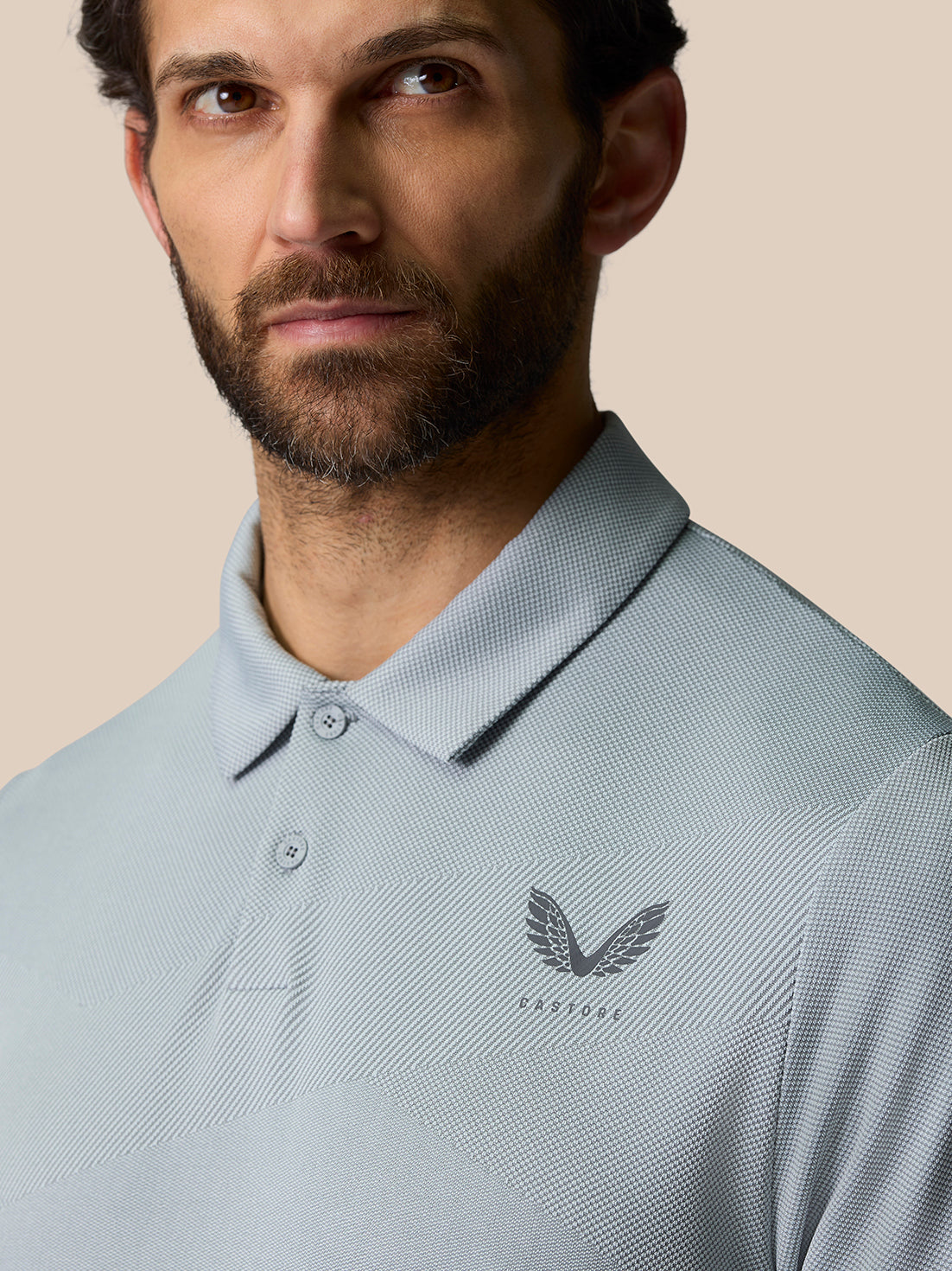 Close up of a man wearing a light grey textured golf polo with a small chest logo and collar