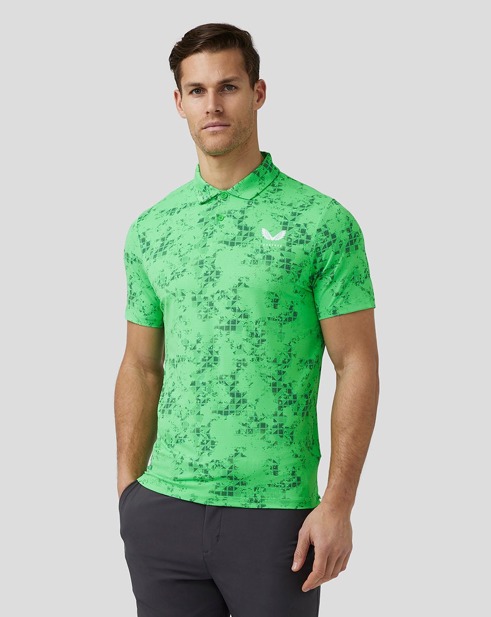Male model wearing lime geometric printed polo with chest logo and dark pants, standing in a relaxed pose