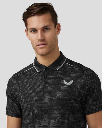 Close-up of a man in a black pixel pattern golf polo with a striped collar and Castore logo on the chest.