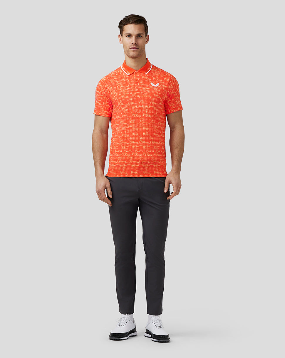 Front view of a male model wearing a bright orange printed golf polo with a ribbed collar and a white chest logo.
