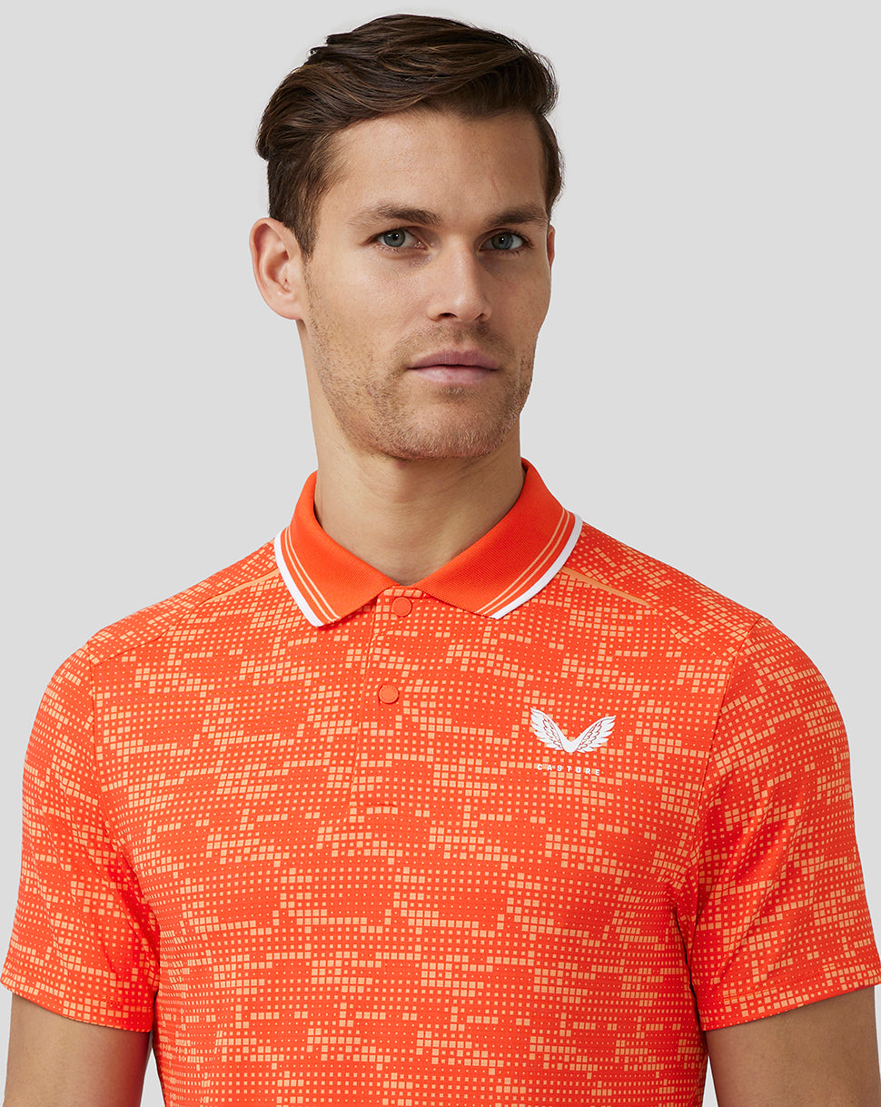 Male model wearing a deep orange printed golf tech polo with white striped collar and Castore logo on chest.