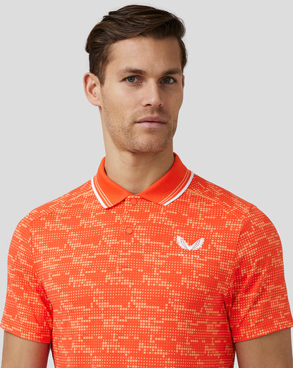 Male model wearing a deep orange printed golf tech polo with white striped collar and Castore logo on chest.