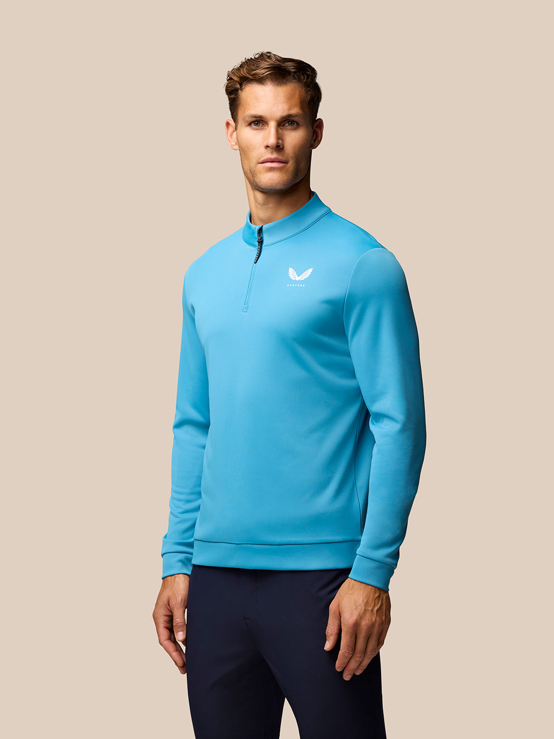 Model wearing corn blue long sleeve golf top with stand collar and centre front quarter zip