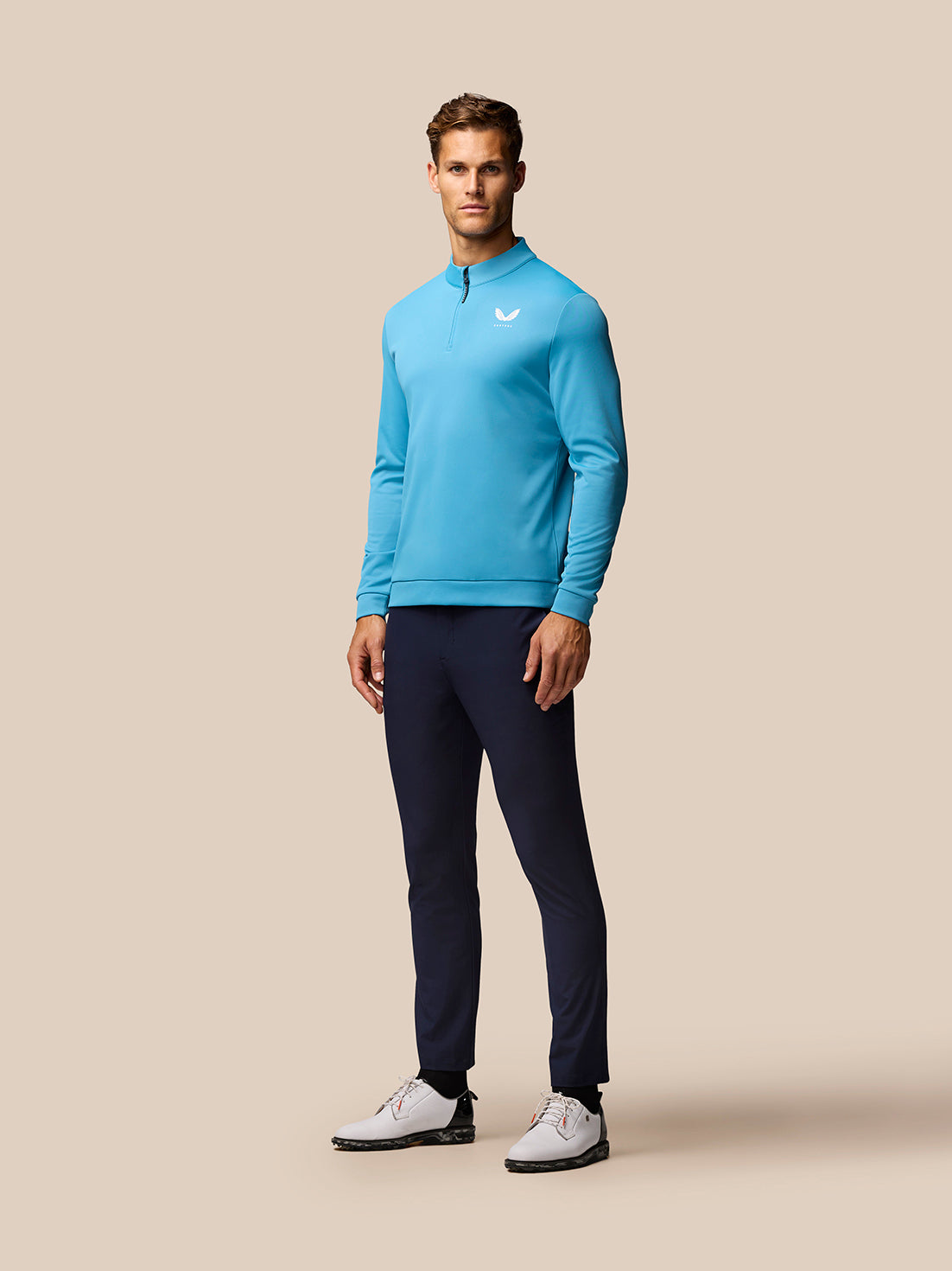 Full-body shot of male model wearing corn blue Club Golf 1/4 Zip Top with navy pants and white golf shoes
