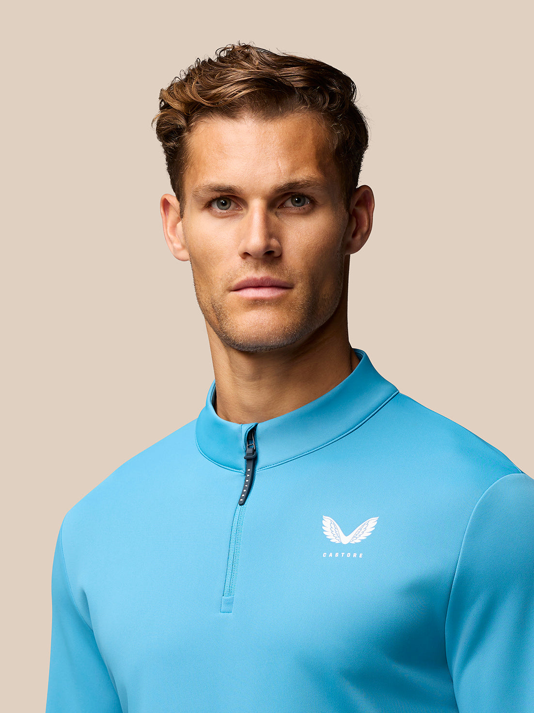 Male model wearing corn blue Club Golf 1/4 Zip Top with stand collar and Castore logo on chest